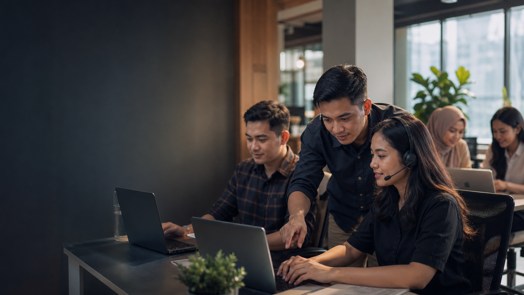 Tim support bekerja bersama di depan laptop